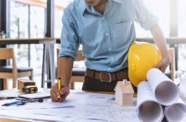 man writing on architectural drawing